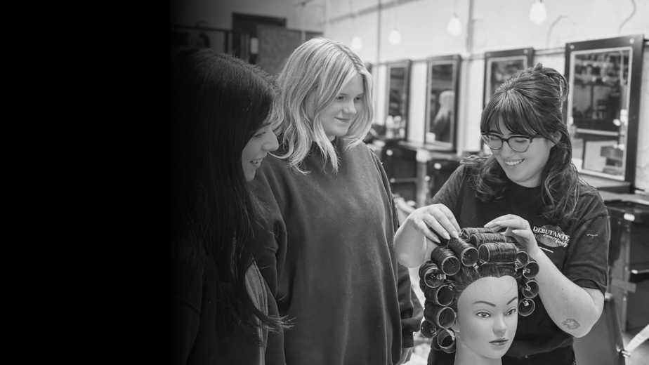 Cosmetology educator putting in a roller set in hair during training at Debutantes School of Beauty.