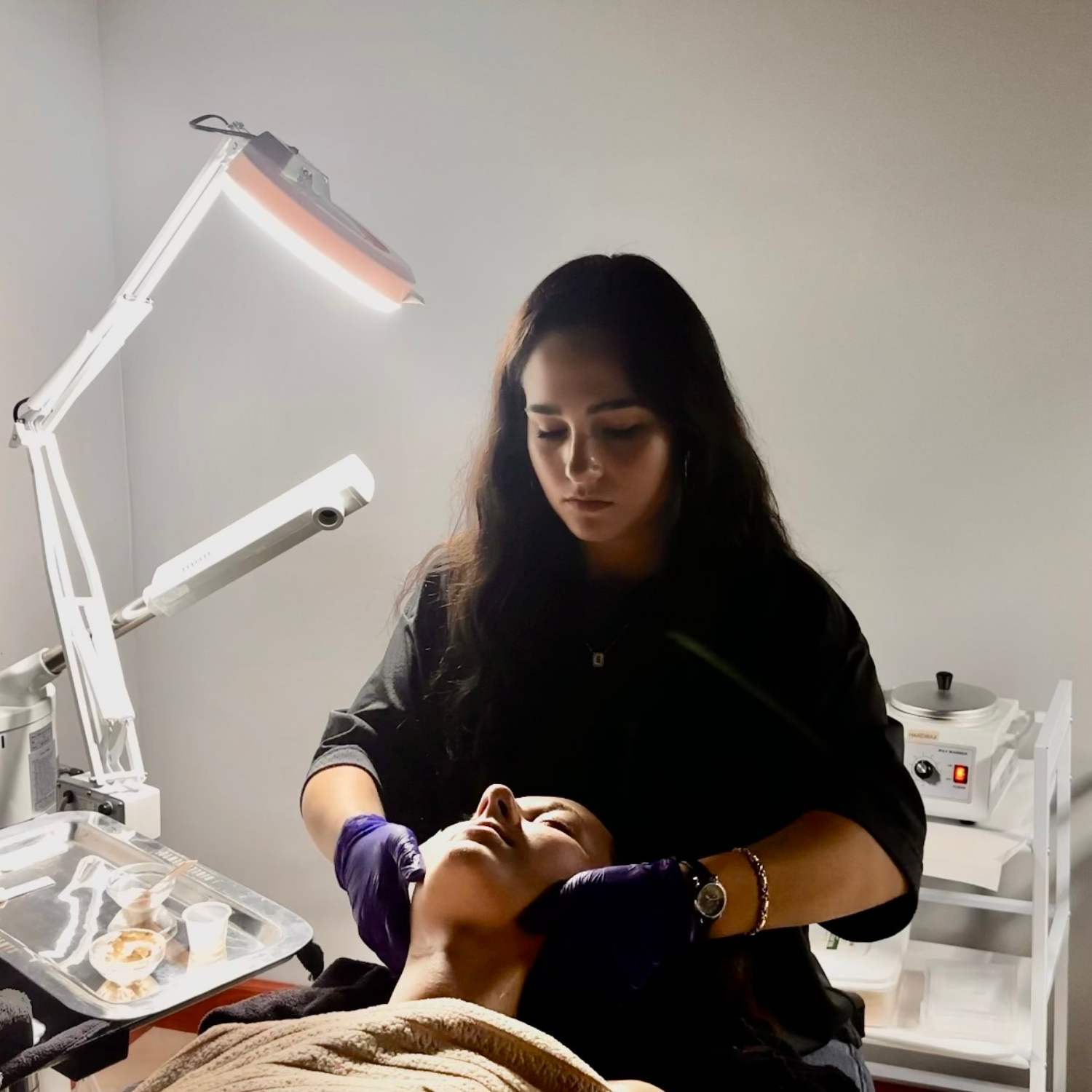 Esthetics student performing a facial treatment during hands-on training at Debutantes School of Beauty.