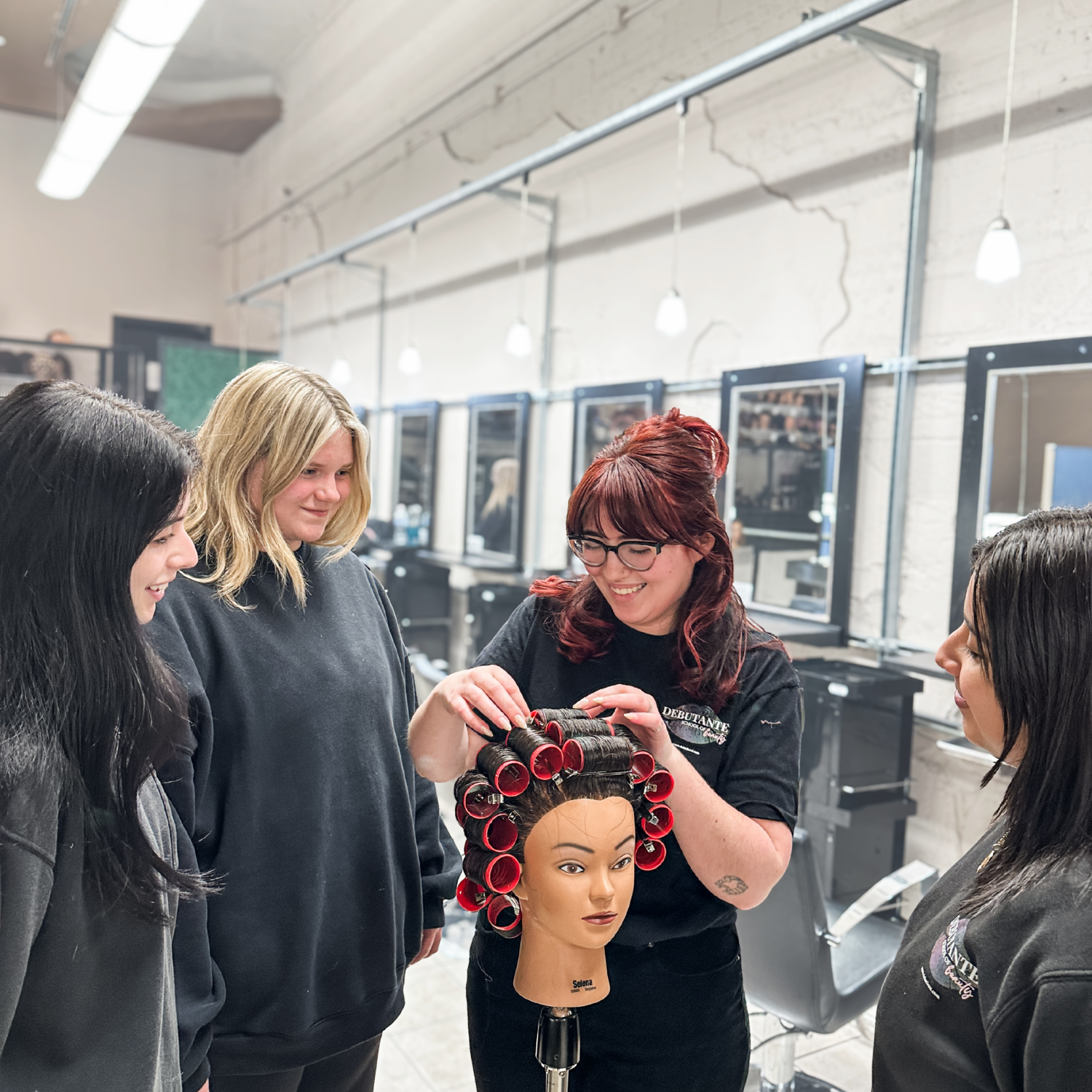 Cosmetology instructor demonstrating roller set technique to students at Debutantes School of Beauty in DeKalb Illinois.