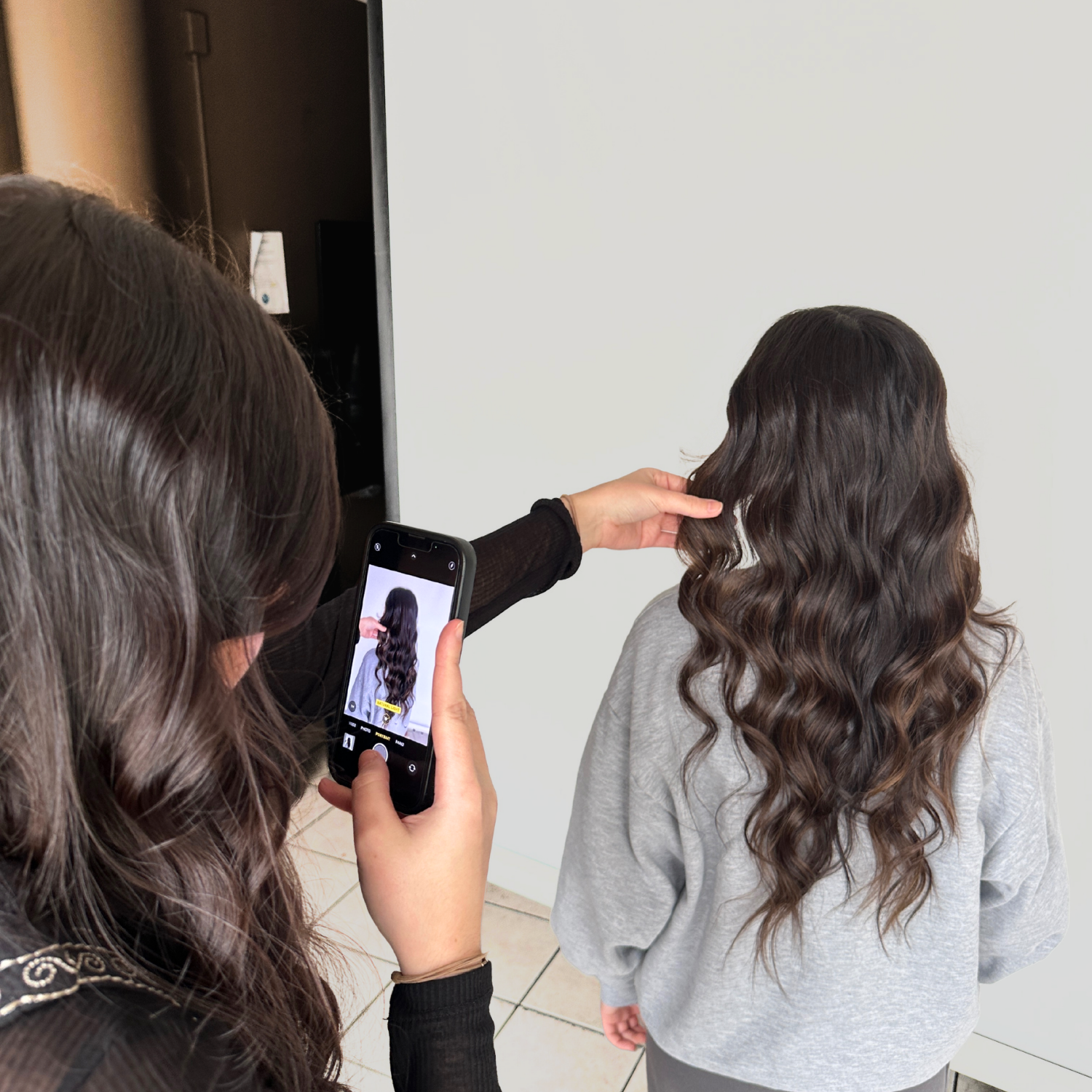 Cosmetology student photographing a finished hairstyle to build a professional portfolio at Debutantes School of Beauty.
