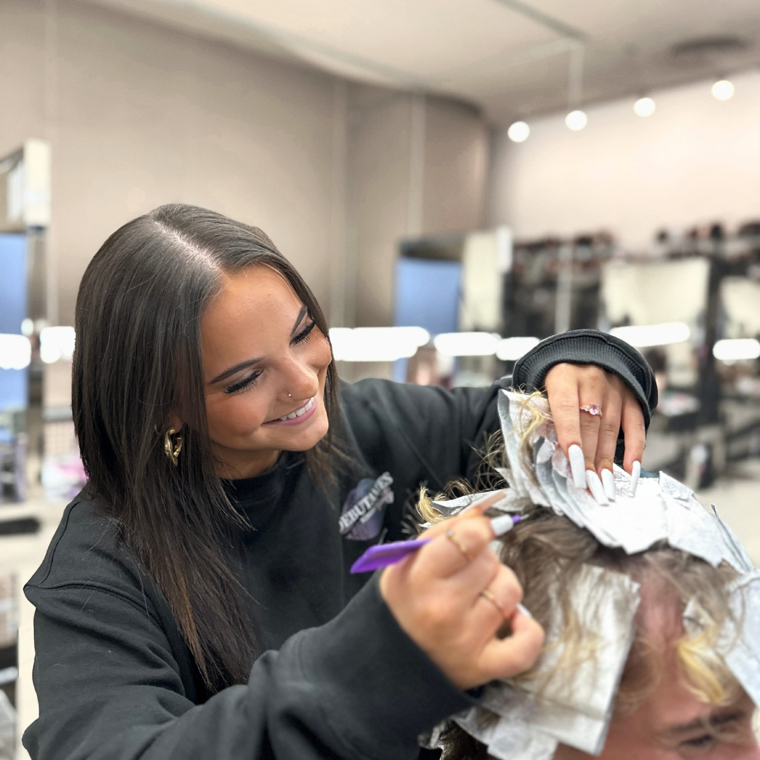 A young female student practicing foiling techniques on a client at Debutantes School of Beauty in DeKalb, IL