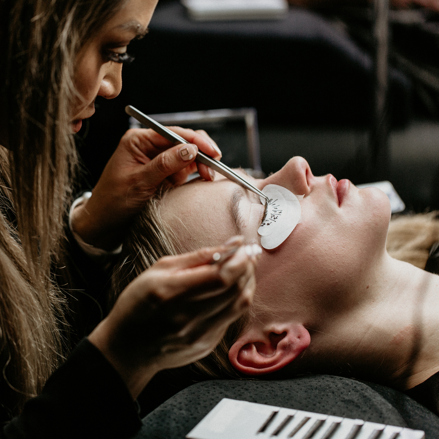 Esthetics student applying eyelash extensions during training at Debutantes School of Beauty in DeKalb Illinois.