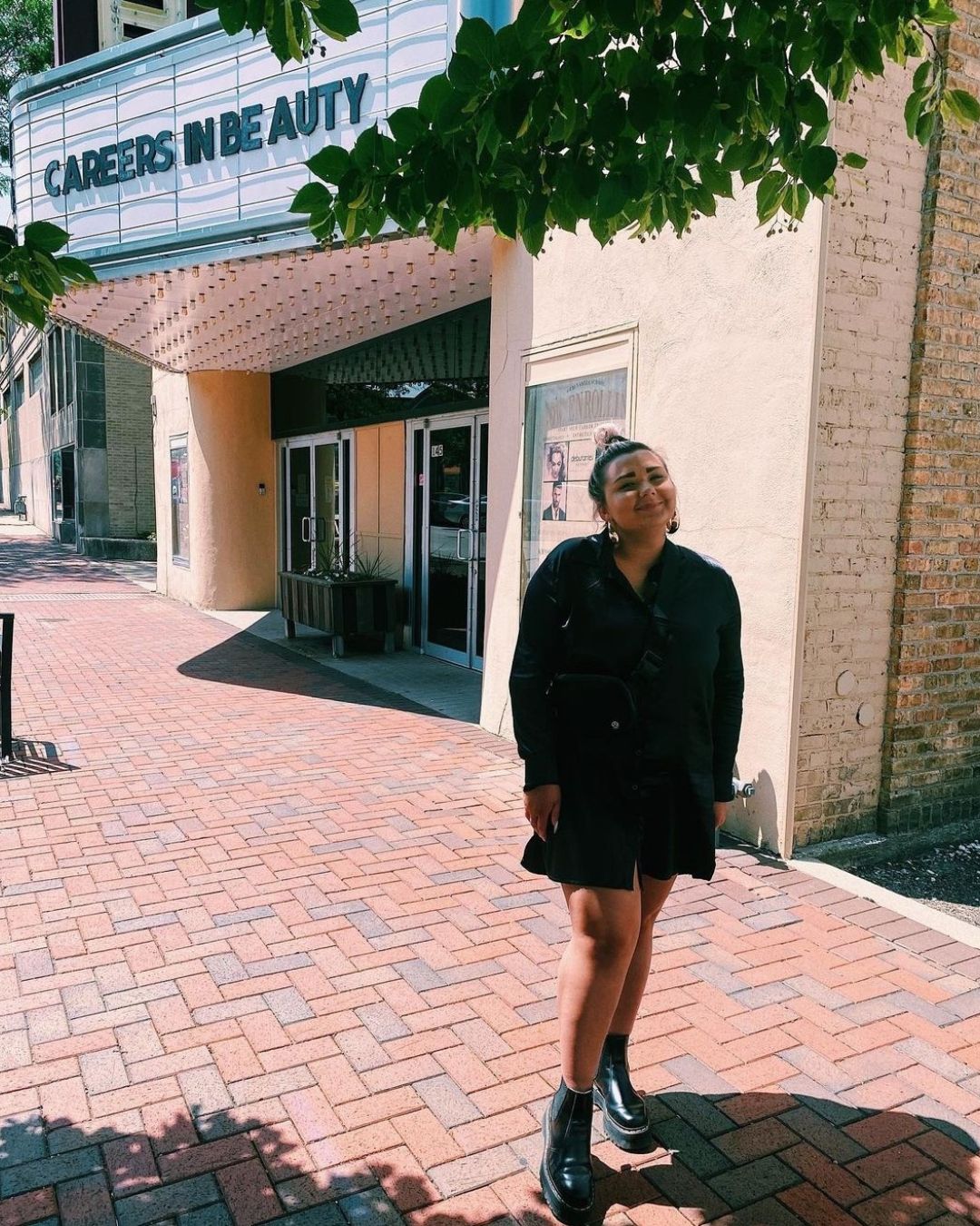 A young female posing in front of a beauty school downtown dekalb.