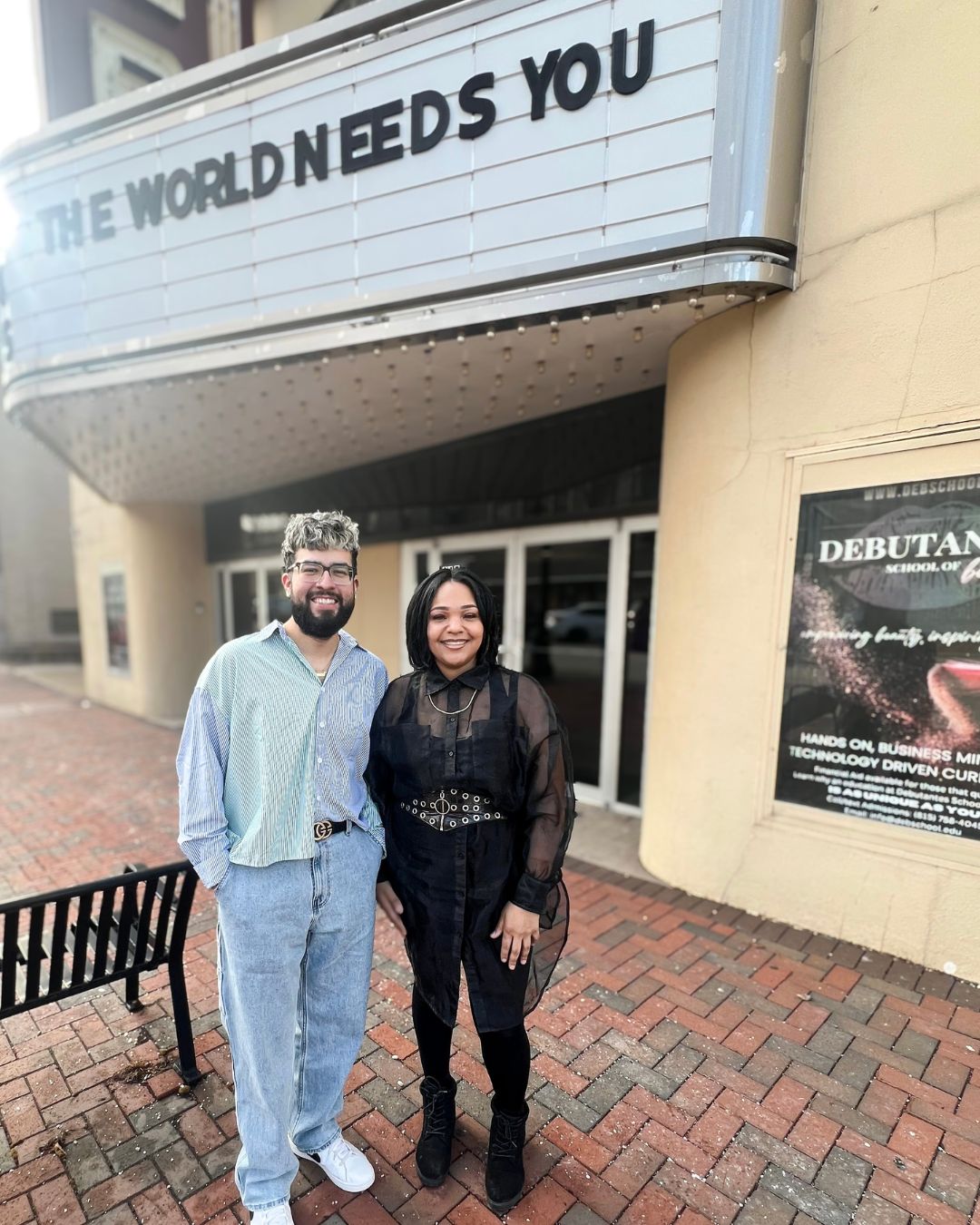 Two people a male and female posing in front of a brick building.